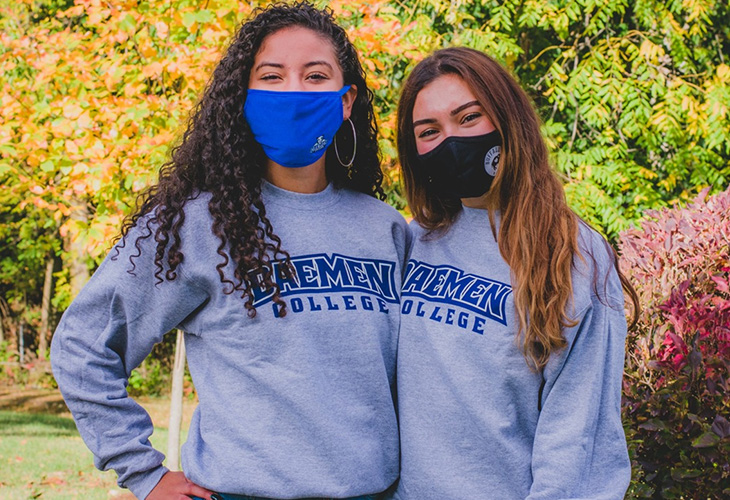 Two female students in masks wearing 鶹AV sweatshirts outside