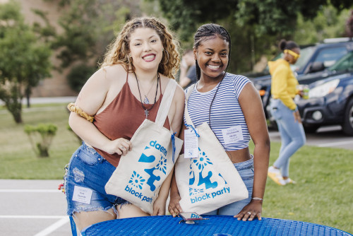 Two female students smiling holding 鶹AV Block Party bags