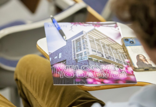 Welcome to 鶹AV orientation book on a desk a student is sitting at